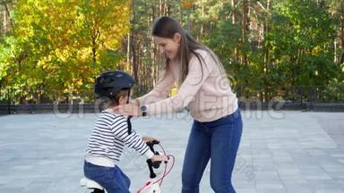 在公园里，一位年轻有<strong>爱心</strong>的母亲在她的小儿子身上戴上并系上了保护自行<strong>车</strong>头盔
